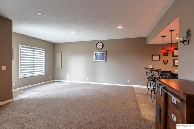 interior space with baseboards, light colored carpet, a textured ceiling, a bar, and recessed lighting