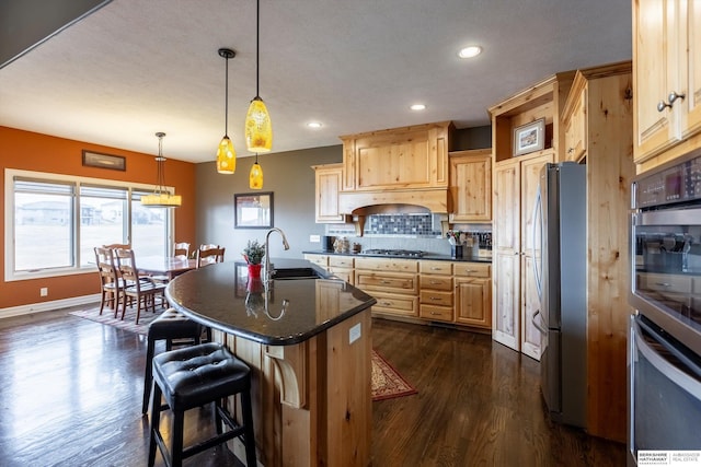 kitchen featuring light brown cabinets, a sink, appliances with stainless steel finishes, tasteful backsplash, and dark wood finished floors