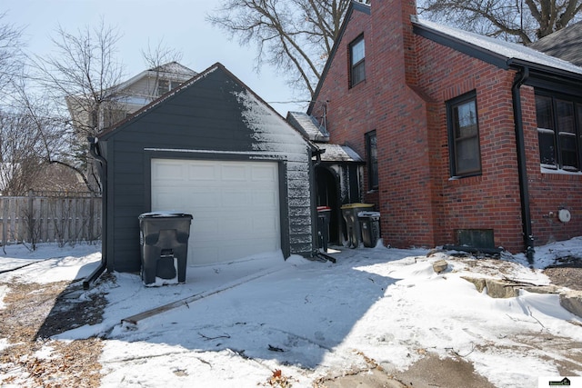 view of snowy exterior with fence and brick siding