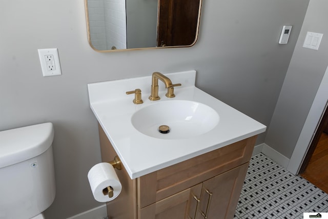 bathroom with toilet, baseboards, and vanity