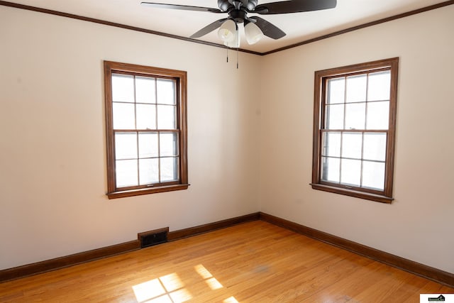 spare room with a wealth of natural light, visible vents, crown molding, and light wood-style flooring