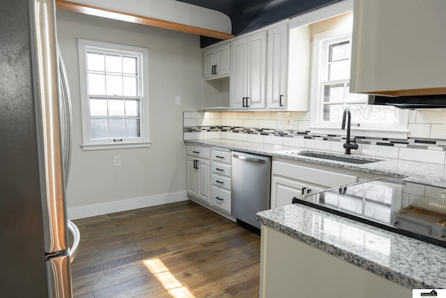 kitchen with tasteful backsplash, baseboards, dark wood finished floors, appliances with stainless steel finishes, and a sink