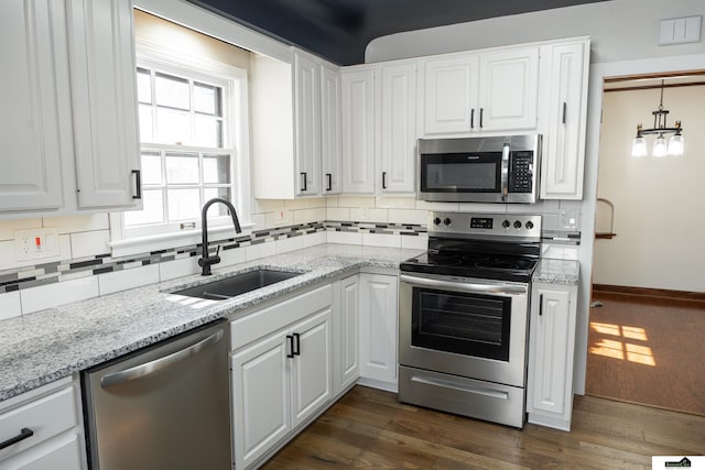 kitchen with dark wood-style floors, tasteful backsplash, appliances with stainless steel finishes, and a sink