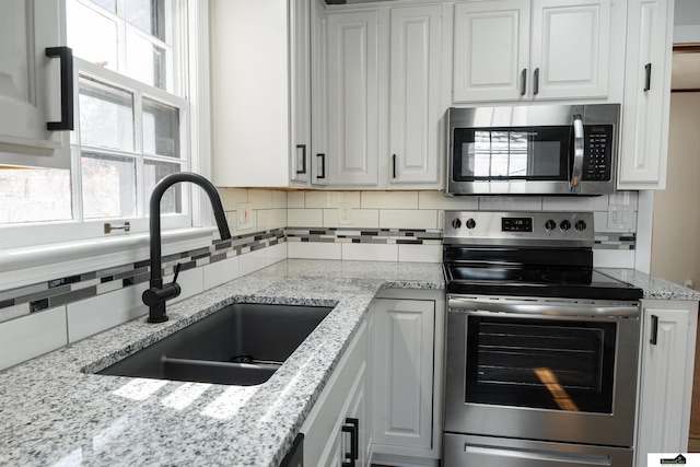 kitchen with stainless steel appliances, a wealth of natural light, a sink, and decorative backsplash