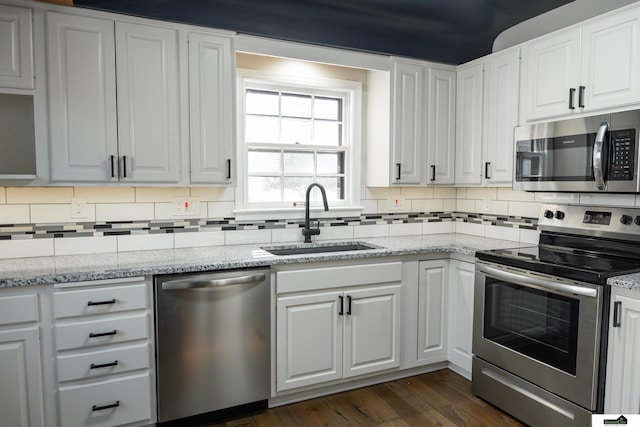 kitchen featuring white cabinetry, appliances with stainless steel finishes, decorative backsplash, and a sink