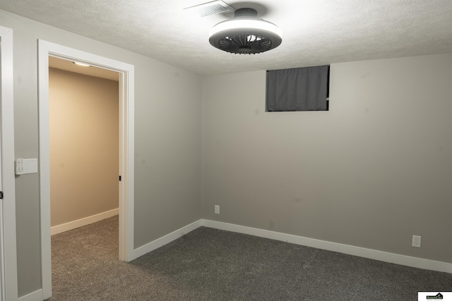 unfurnished room featuring visible vents, baseboards, dark colored carpet, and a textured ceiling