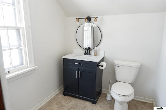 bathroom with toilet, lofted ceiling, baseboards, and vanity