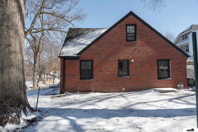 snow covered property featuring brick siding