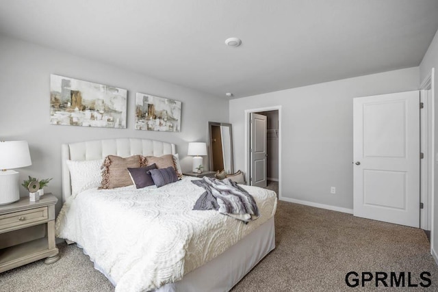 carpeted bedroom with a spacious closet and baseboards