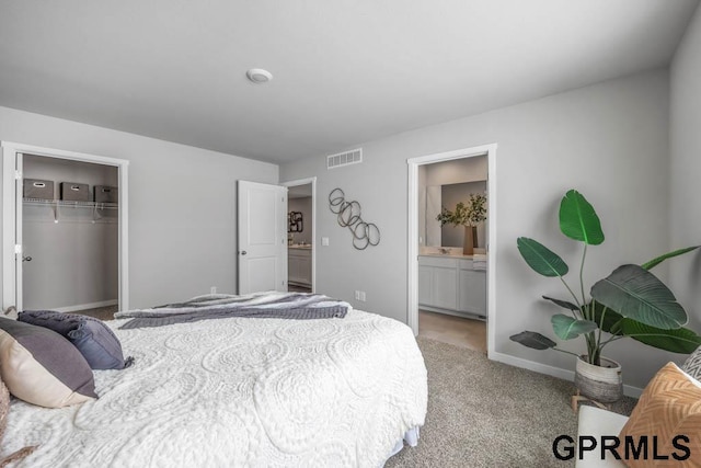 bedroom featuring baseboards, visible vents, connected bathroom, light colored carpet, and a closet