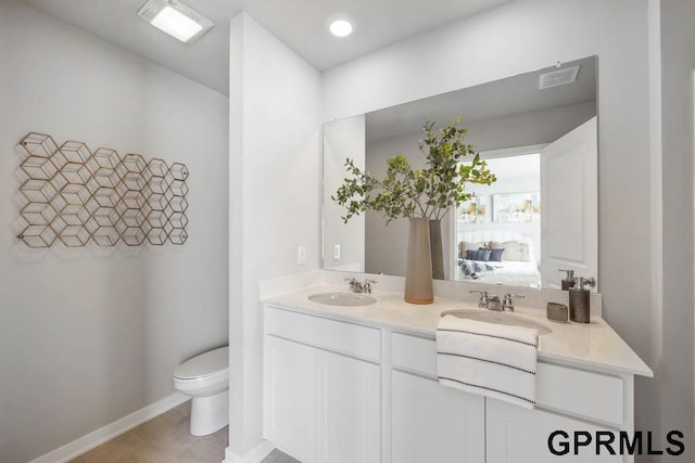 bathroom with double vanity, a sink, toilet, and ensuite bathroom