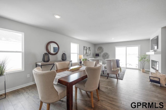 dining space with plenty of natural light, wood-type flooring, and a fireplace