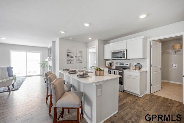 kitchen featuring appliances with stainless steel finishes, light countertops, a breakfast bar area, and wood finished floors