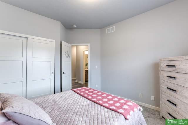 bedroom with a closet, carpet flooring, visible vents, and baseboards