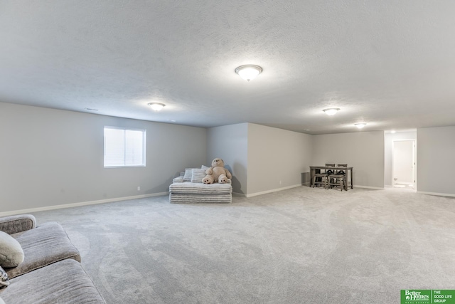 living area featuring light carpet, a textured ceiling, and baseboards