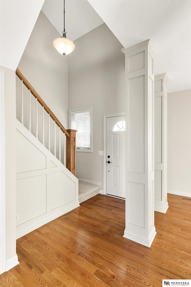 foyer entrance with stairway, a high ceiling, baseboards, and wood finished floors