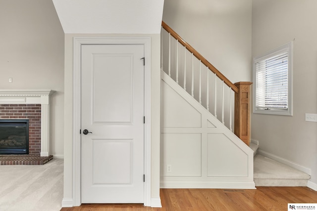 stairway with a brick fireplace, baseboards, and wood finished floors