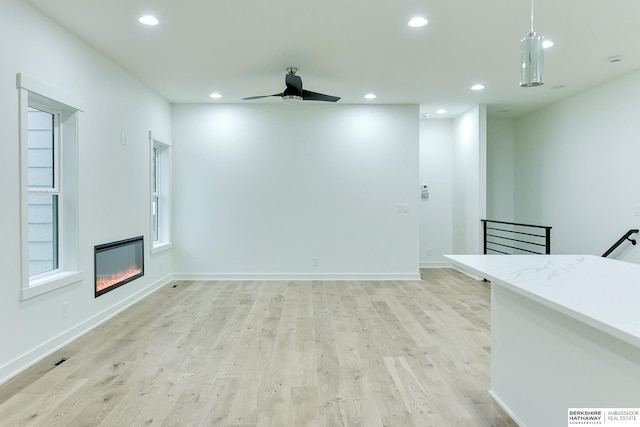 unfurnished living room with baseboards, a ceiling fan, a glass covered fireplace, light wood-style floors, and recessed lighting