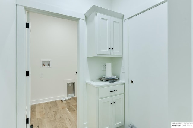 clothes washing area with cabinet space, hookup for a washing machine, and light wood-style flooring