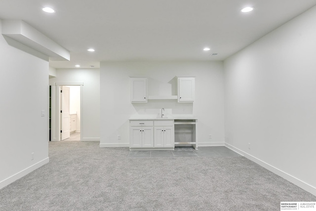 unfurnished living room featuring recessed lighting, a sink, and light colored carpet