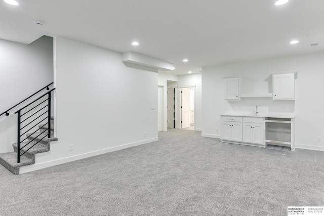 unfurnished living room featuring wine cooler, recessed lighting, light colored carpet, baseboards, and stairs