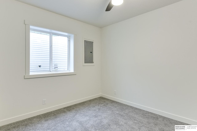 spare room featuring a ceiling fan, carpet flooring, electric panel, and baseboards