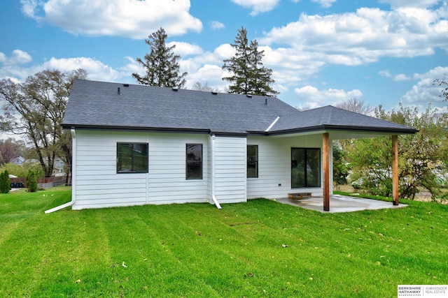 rear view of property featuring a shingled roof, a patio area, and a yard