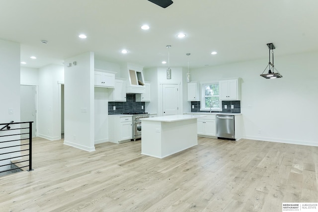 kitchen featuring light wood finished floors, appliances with stainless steel finishes, white cabinets, and backsplash