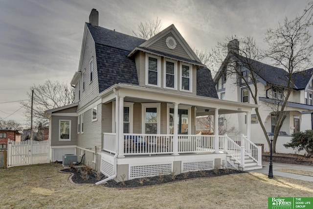 dutch colonial featuring a shingled roof, a chimney, covered porch, fence, and central air condition unit