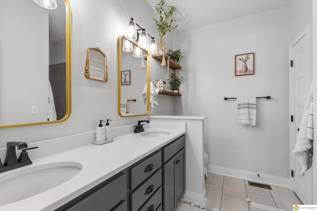 bathroom with baseboards, double vanity, a sink, and tile patterned floors