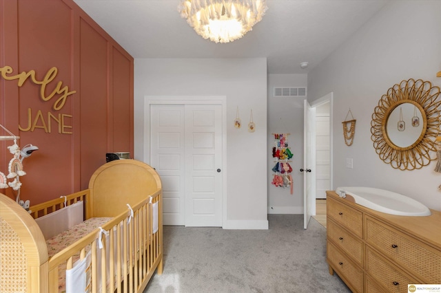 bedroom featuring a closet, light colored carpet, visible vents, a chandelier, and baseboards