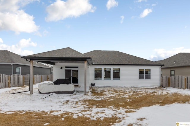 snow covered rear of property with a gazebo, a shingled roof, and fence