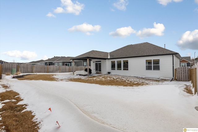 view of front of house featuring a fenced backyard and roof with shingles