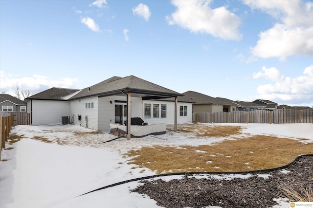 snow covered house with cooling unit and a fenced backyard