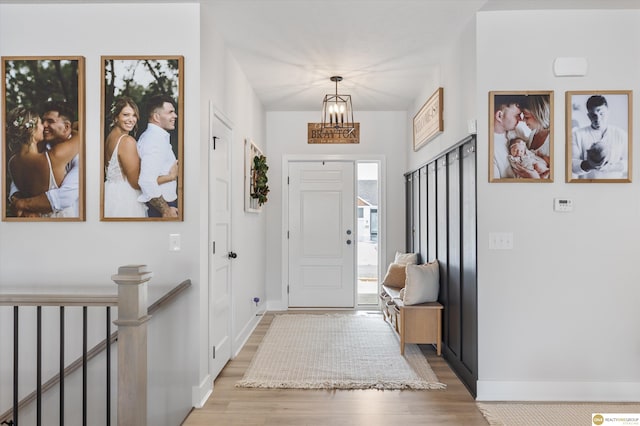 foyer entrance featuring a notable chandelier, light wood-style flooring, and baseboards