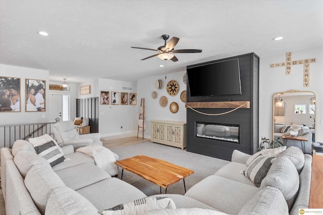 living room with a large fireplace, ceiling fan, baseboards, and recessed lighting