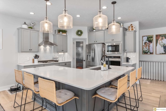 kitchen featuring stainless steel appliances, light wood-type flooring, gray cabinets, and a sink