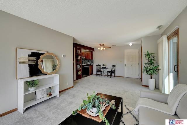 carpeted living room with visible vents, ceiling fan, and a textured ceiling