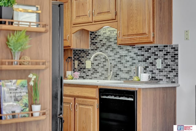 kitchen with black dishwasher, light countertops, a sink, and decorative backsplash