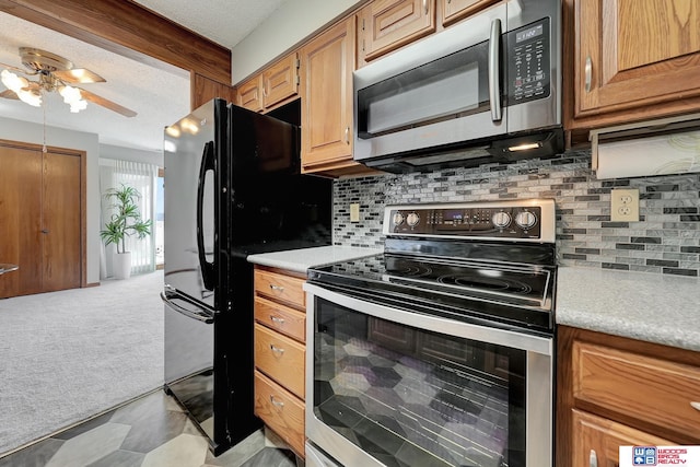 kitchen with a textured ceiling, stainless steel appliances, light countertops, and light colored carpet