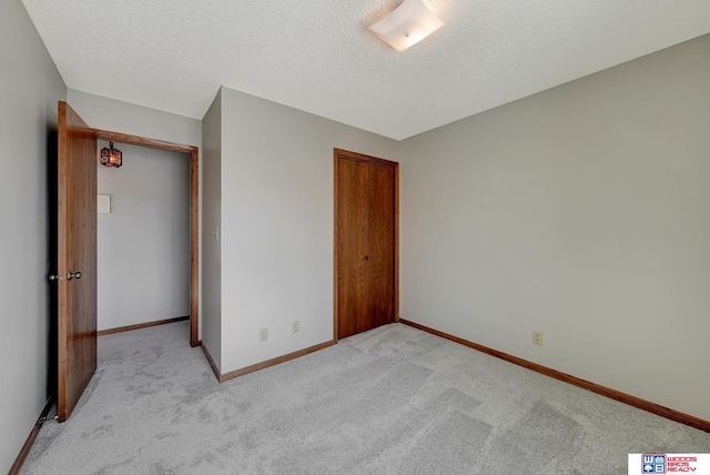 unfurnished bedroom with baseboards, a textured ceiling, and light colored carpet