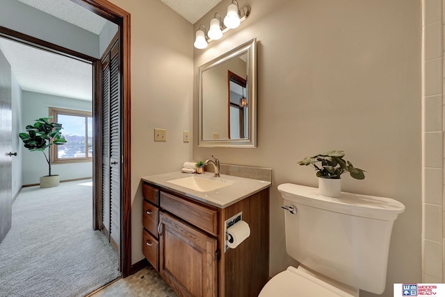 bathroom with baseboards, a textured ceiling, toilet, and vanity