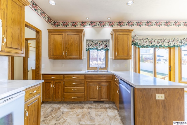 kitchen with brown cabinets, light countertops, stainless steel dishwasher, a sink, and a peninsula