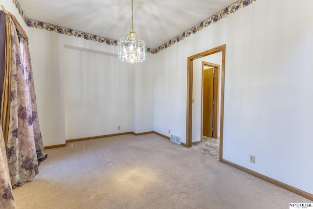 empty room featuring a chandelier, carpet, visible vents, and baseboards