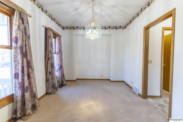 unfurnished room featuring an inviting chandelier, carpet, visible vents, and baseboards