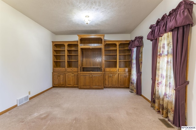 unfurnished living room featuring baseboards, visible vents, and light colored carpet