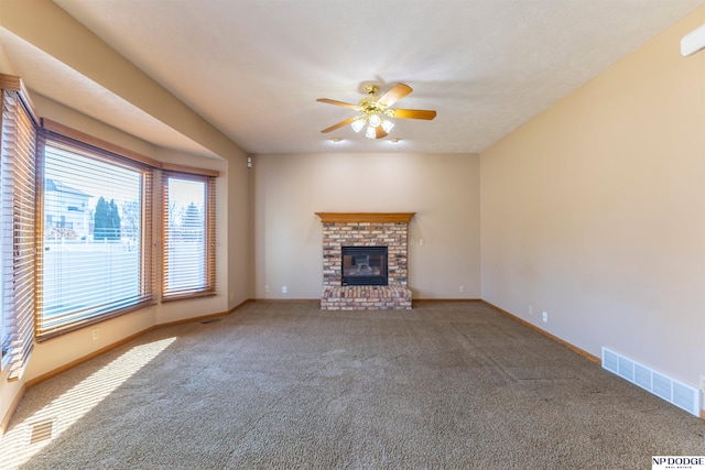 unfurnished living room with ceiling fan, carpet floors, visible vents, baseboards, and a brick fireplace