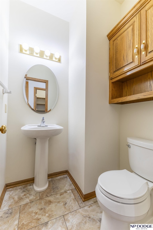 half bathroom featuring baseboards and toilet