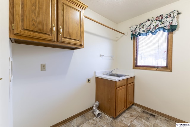 washroom with cabinet space, hookup for an electric dryer, a sink, and baseboards