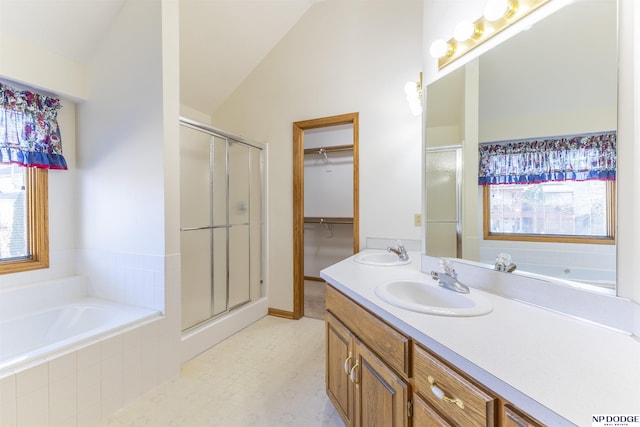 full bathroom featuring a stall shower, vaulted ceiling, a sink, and double vanity